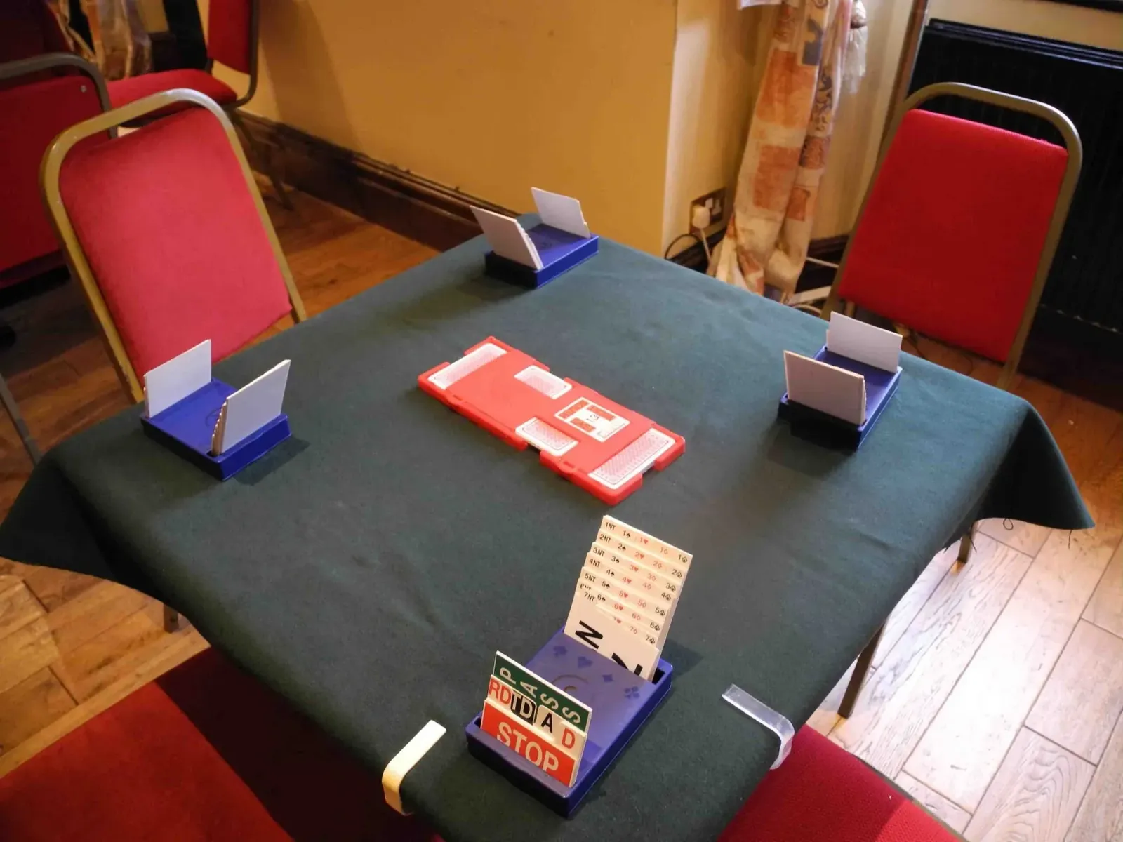 A bridge table set up with bidding boxes and a board, ready for a face to face session