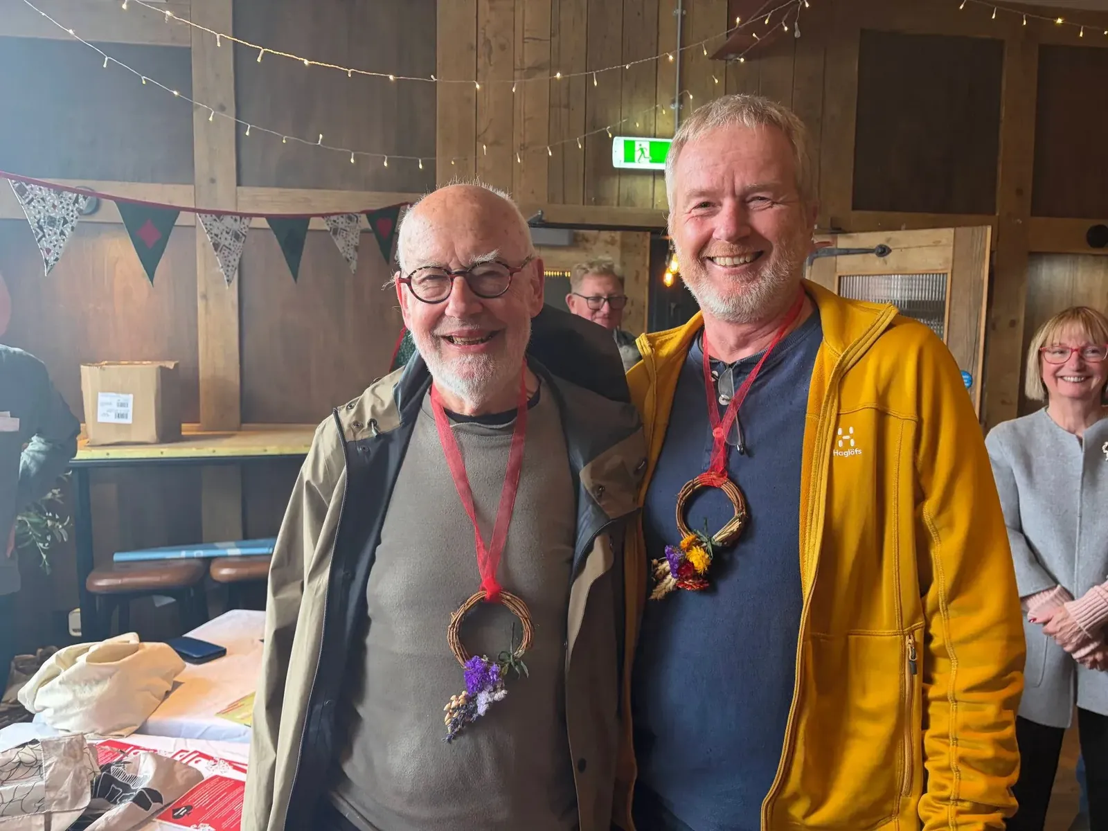 Two Cafe Bridge winners wearing wreath medals and smiling