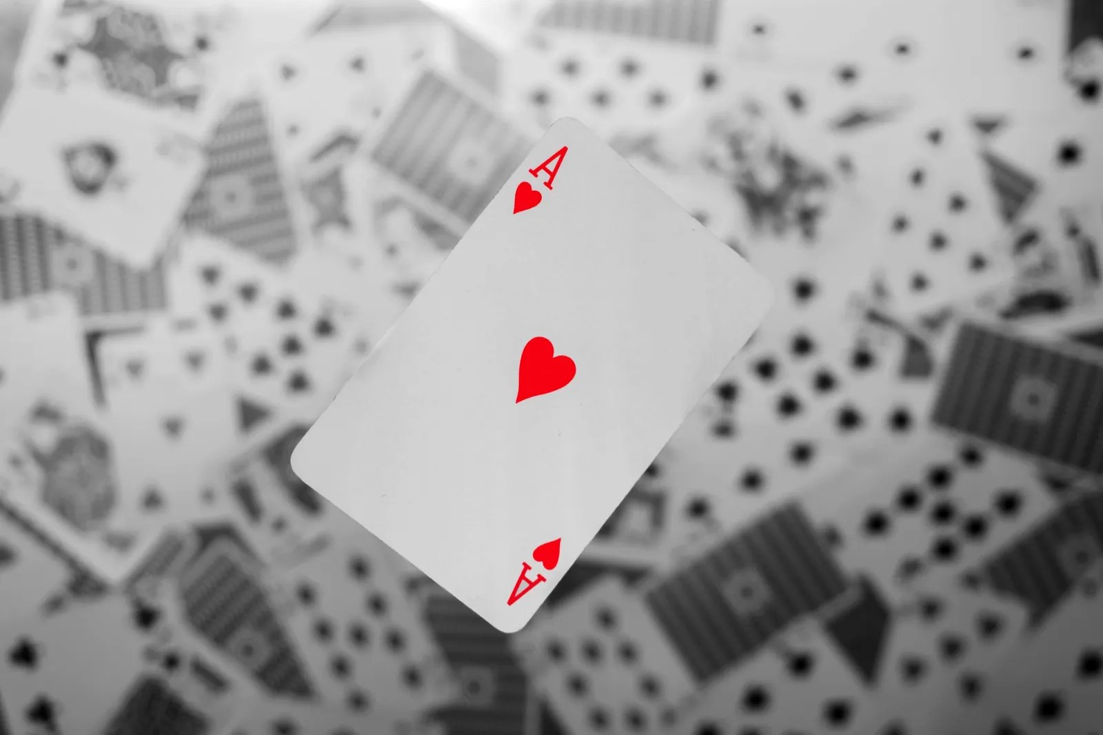 The ace of hearts in sharp focus above a scatter of blurred cards